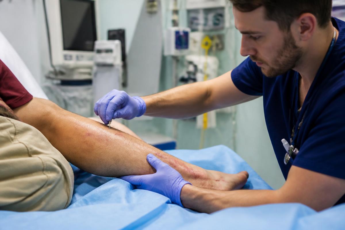 Clinician assessing a swollen lower leg for compartment syndrome at the bedside